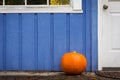 An orange pumpkin on the front porch of a purple house. Royalty Free Stock Photo