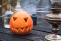 Orange pumpkin for halloween, jack-o-lantern with scary carved eyes, mouth.Candles, old lamp, spiderweb on wooden table near barn Royalty Free Stock Photo