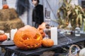 Orange pumpkin for halloween, jack-o-lantern with scary carved eyes, mouth.Candles, old lamp, spiderweb on wooden table Royalty Free Stock Photo