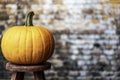 Orange pumpkin on wood stool isolated against brick wall Royalty Free Stock Photo