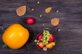 Orange pumpkins with apples and pears in a basket with grapes, nuts and leaves on a brown wooden table. View from above Royalty Free Stock Photo