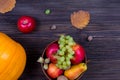 Orange pumpkins with apples and pears in a basket with grapes, nuts and leaves on a brown wooden table. View from above Royalty Free Stock Photo