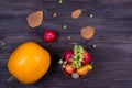 Orange pumpkins with apples and pears in a basket with grapes, nuts and leaves on a brown wooden table. View from above Royalty Free Stock Photo