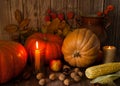 Orange pumpkins, burning candles, walnuts and chestnuts, corn, physalis, ceramic vase, autumn leaves on a wooden background. Royalty Free Stock Photo