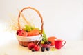 Orange pumpkins, grapes and ginger berries, a red mug with juice, pomegranate fruits on a table and in a basket on a white Royalty Free Stock Photo