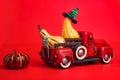 Orange pumpkins in red toy truck with human skeleton on red background. Happy Halloween