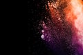 Orange purple powder explosion on black background. Orange purple color dust splash