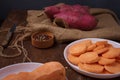 Orange, purple raw sweet potatoes, yam slices on burlap, wooden rustic table, allspice pepper peas. Farm harvest, organic Royalty Free Stock Photo