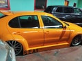 Orange race car parked in a parking lot with other cars.