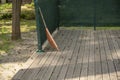 orange rake on a wooden platform, against the background of a park Royalty Free Stock Photo