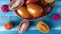 Orange and red oval tomatoes in a basket on a blue background close up top view