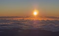 orange red sunrise, sun rising above the fluffy clouds with sunbeam rays and lens flare, taken from top of pico del teide tenerife
