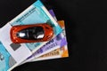 An orange red toy car placed on bundles of money shot over black surface with copy space