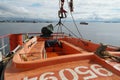 Orange rescue boat built from glass reinforced plastic material with outboard engine is secured by davit. Royalty Free Stock Photo