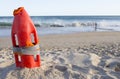 Orange rescue buoy planted on sand beach. Little boy close to th Royalty Free Stock Photo
