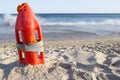 Orange rescue buoy planted on sand beach Royalty Free Stock Photo