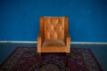 Orange Retro Armchair With Velvet Upholstery On A Blue Wall Background.On The Floor There Is A Red Carpet With A Pattern