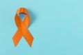 Orange ribbon on blue background . Healthcare and medicine concept. Multiple Sclerosis awareness. Leukemia awareness. Empty text Royalty Free Stock Photo