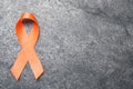 Orange ribbon on grey table, top view with space for text. Multiple sclerosis awareness Royalty Free Stock Photo