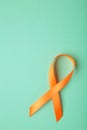 Orange ribbon on mint background . Healthcare and medicine concept. Multiple Sclerosis awareness. Leukemia awareness. Empty text