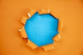 Orange ripped open paper on blue paper background,space for your message on torn paper Royalty Free Stock Photo