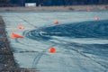 Orange road cones lying destroyed on concrete beton plates with rubber traces left by sport cars tires during drifting competiti