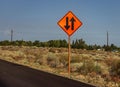 An orange road sign in na desert with an arrow pointing up and one pointing down Royalty Free Stock Photo