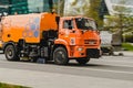 orange road-washing and sweeping truck drives down the street of the city. Daily cleaning of streets in the city Royalty Free Stock Photo