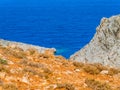 Orange rocky hill contrasting the deep blue sea in the background Royalty Free Stock Photo
