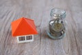 Orange roof houses and coins in bottles and The idea of saving money, buying a home and mortgage real estate and investing in a Royalty Free Stock Photo