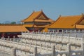 Orange roofs of traditional chinese buildings with white marble pillars in foreground