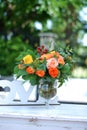Orange Roses in Clear Glass Vase on White Table with Blurred Green Garden Background. Floral Arrangement. Spring or Royalty Free Stock Photo
