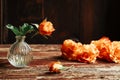 Orange roses in the vase and on the old wooden table Royalty Free Stock Photo