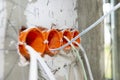 Orange, round junction box mounted in the white wall with protruding electric cables. Royalty Free Stock Photo