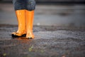 Orange rubber boots in a dirty puddle