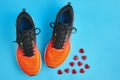 Orange running shoes and red decorative glass hearts scattered on a blue background