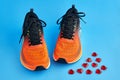 Orange running shoes and red decorative glass hearts scattered on a blue background