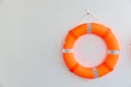 Orange safety torus or lifebuoy hanging on white wall background. Lifebuoy hanging on a cement wall.  Help and Security concept. Royalty Free Stock Photo