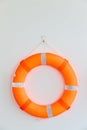 Orange safety torus or lifebuoy hanging on white wall background. Lifebuoy hanging on a cement wall.  Help and Security concept. Royalty Free Stock Photo