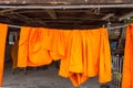 Orange and saffron robes of Buddhist monks hanging on wooden.Thailand. Royalty Free Stock Photo