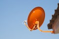 Orange satellite dish with blue sky background