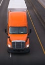 Orange semi truck with dry van trailer on the road top view