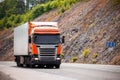 Orange truck moving by a road