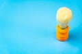 Orange shaving brush on blue background, copy space