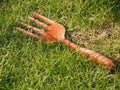 Orange shoveling fork on green grass