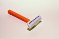 Orange single-blade razor on white background