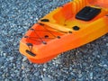 Orange single seater sea kayak for fishing on the pebble seashore