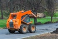 Orange Skid steer loader is on the road. Royalty Free Stock Photo