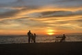 Orange sky background with clouds at sunset and black silhouettes of people against the sky and sea on a summer evening. Seascape Royalty Free Stock Photo