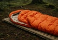 Orange Sleeping Bag on a Camping Mat in a Forest Royalty Free Stock Photo